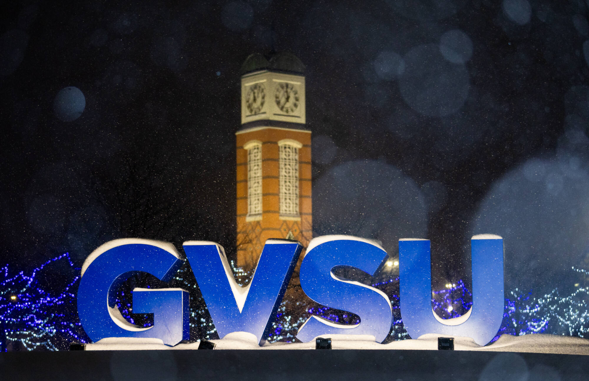 Snow falls around the GVSU letters with the clock tower visible in the background on Valley Campus during a snow storm on Jan 19th.